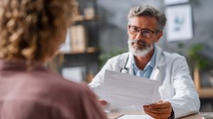A patient discusses their recent emergency room visit with their primary care doctor, using the discharge papers to ensure continuity of care.